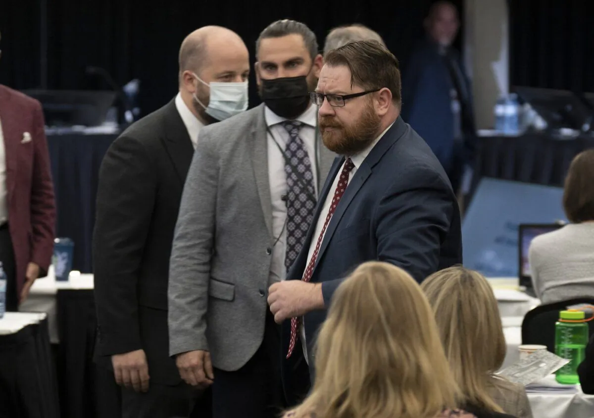 Security escort Freedom Corp. counsel Brendan Miller out of the hearing room at the Public Order Emergency Commission hearing in Ottawa on Nov. 22, 2022. (The Canadian Press/Adrian Wyld)