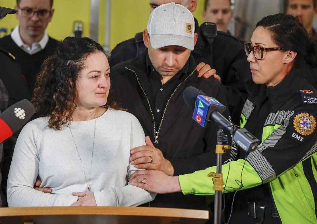 Paramedic Jayme Erickson, left, who was called to a crash last week and didn’t know she was trying to save her own daughter because the injuries were too severe, is comforted by her husband Sean Erickson, centre, and friends as she speaks to the media in Airdrie, Alta., Nov. 22, 2022. (The Canadian Press/Jeff McIntosh)
