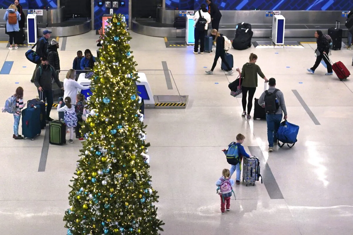 A family passes a Christmas tree while checking their bags for a flight at Logan International Airport in Boston, on Nov. 21, 2022. (Charles Krupa/AP Photo)