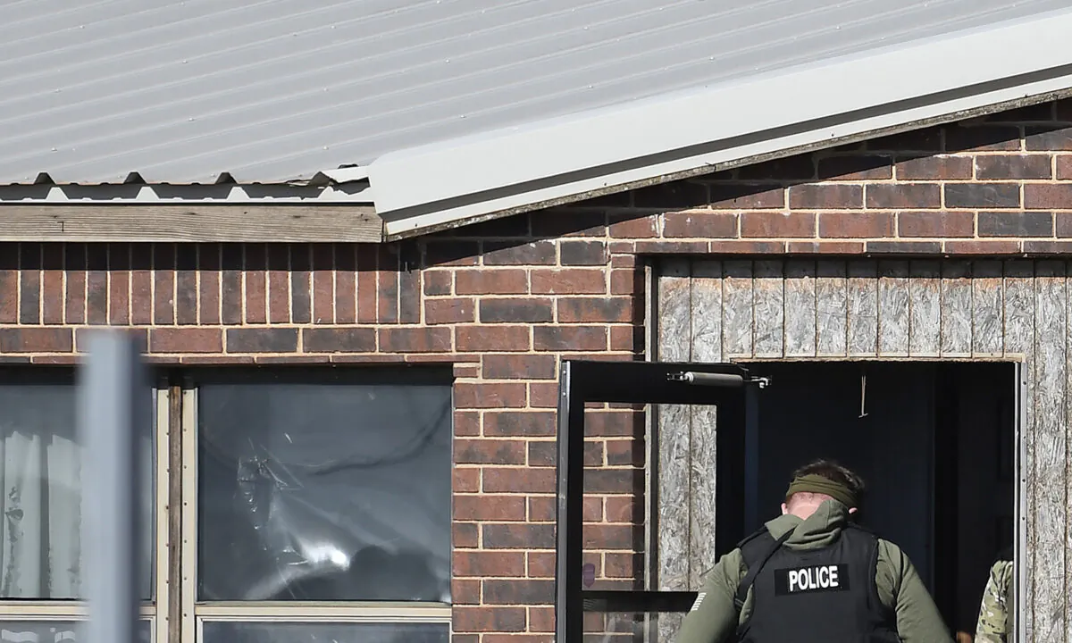A law enforcement officer enters a residence near Lacey, Okla., on Nov. 21, 2022. (Billy Hefton/The Enid News & Eagle via AP)