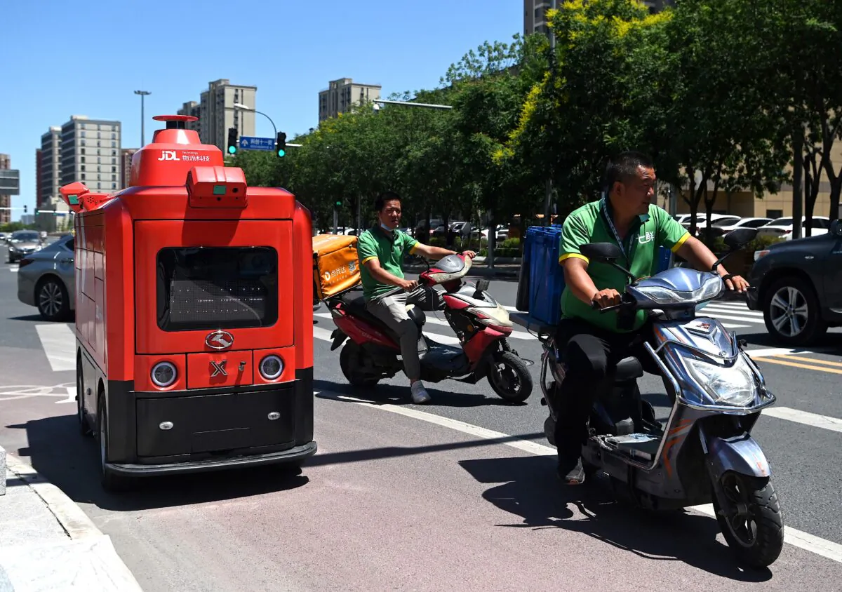 Delivery workers drive past an autonomous vehicle from Chinese e-commerce giant JD.com delivering goods to customers in Beijing on June 18, 2021. (Noel Celis/AFP via Getty Images)