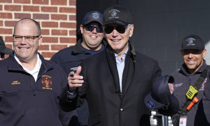 2022 年 11 月 24 日，在感恩节访问马萨诸塞州楠塔基特消防局的消防员期间，乔·拜登总统（中）站在楠塔基特消防局局长迈克尔·克兰森（左）旁边。（Susan Walsh/AP照片）