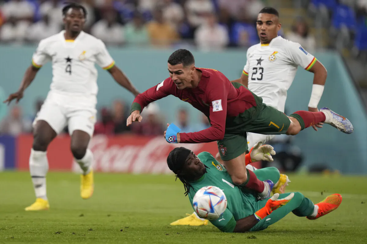 Portugal's Cristiano Ronaldo, up, collides with Ghana's goalkeeper Lawrence Ati-Zigi during the World Cup group H soccer match between Portugal and Ghana, at the Stadium 974 in Doha, Qatar, on Nov. 24, 2022. (Darko Bandic/AP Photo)