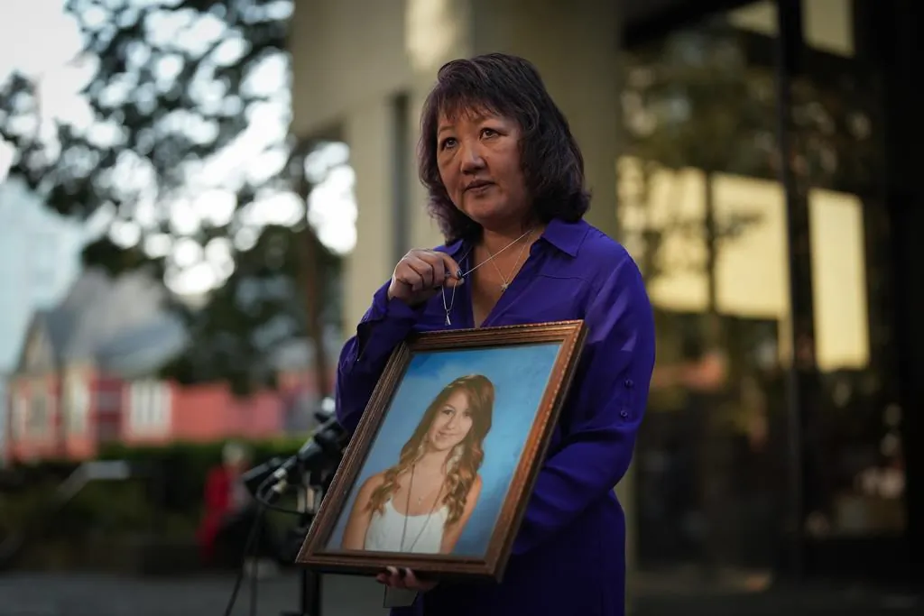 Carol Todd holds a photo of her late teenage daughter Amanda Todd, who died by suicide in 2012, and the necklace she was wearing in the school photo, outside B.C. Supreme Court after sentencing for the Dutch man who was accused of extorting and harassing her daughter, in New Westminster, B.C., on Oct. 14, 2022. (The Canadian Press/Darryl Dyck)