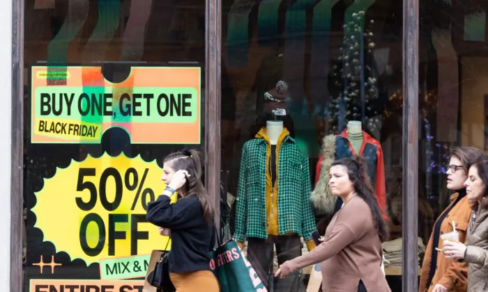 Shoppers walk past sale signs in the outdoor shopping area of Avalon during Black Friday in Alpharetta, Ga., on Nov. 25, 2022. (Jessica McGowan/Getty Images)