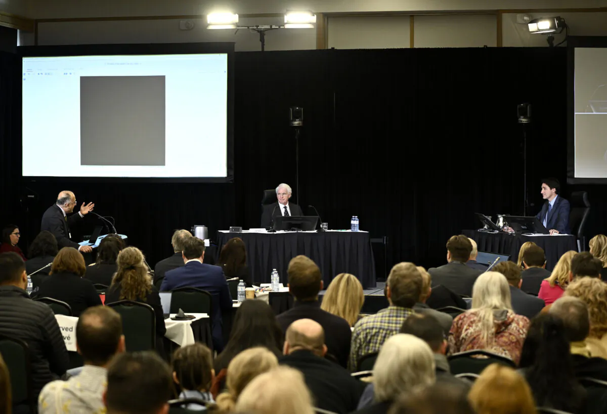 A heavily redacted document is shown on a projector by Sujit Chowdhury (L), counsel for the Canadian Constitution Foundation, as he questions Prime Minister Justin Trudeau at the Public Order Emergency Commission, in Ottawa on Nov. 25, 2022. (The Canadian Press/Justin Tang)