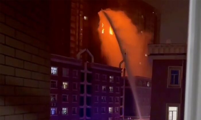Firefighters spray water on a fire at a residential building in Urumqi in western China's Xinjiang Region on Nov. 24, 2022, in a still from video. (AP Photo)