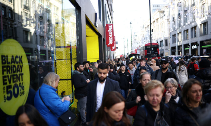 2022 年 11 月 25 日，伦敦牛津街黑色星期五期间，人们走过商店橱窗里的黑色星期五标牌。（Henry Nicholls/路透社）