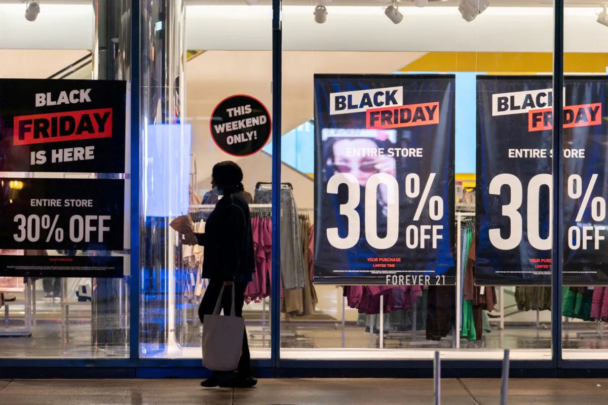A woman passes by signs advertising sales of Black Friday in the Manhattan borough of New York City, N.Y., on Nov. 26, 2021. (Jeenah Moon/Reuters)