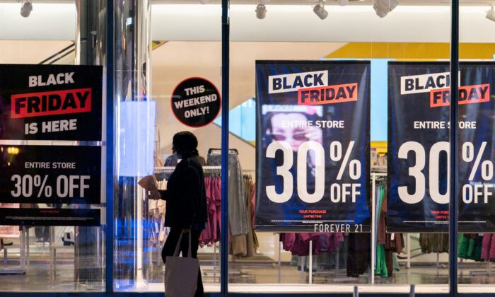 A pistillate   passes by signs advertizing  income  of Black Friday successful  the Manhattan borough of New York City, N.Y., connected  Nov.  26, 2021. (Jeenah Moon/Reuters)