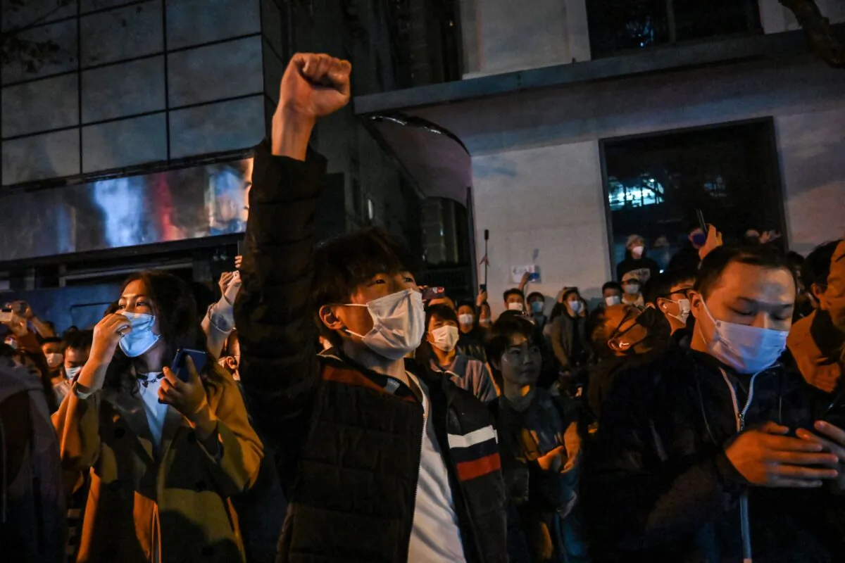 People sing slogans while gathering on a street in Shanghai to protest on Nov. 27, 2022. (Hector Retamal/AFP via Getty Images)