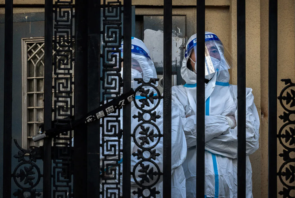 Epidemic control workers stand guard behind the locked gate at an apartment building in the Central Business District in Beijing on Nov. 26, 2022. (Kevin Frayer/Getty Images)