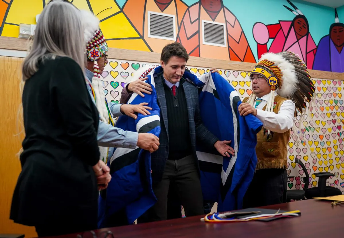 Prime Minister Justin Trudeau, middle receives a blanket from Chakastaypasin Chief Calvin Sanderson, left, and James Smith Cree Nation Chief Wally Burns, right, at James Smith Cree Nation, Sask., on November 28, 2022. (Heywood Yu/The Canadian Press)