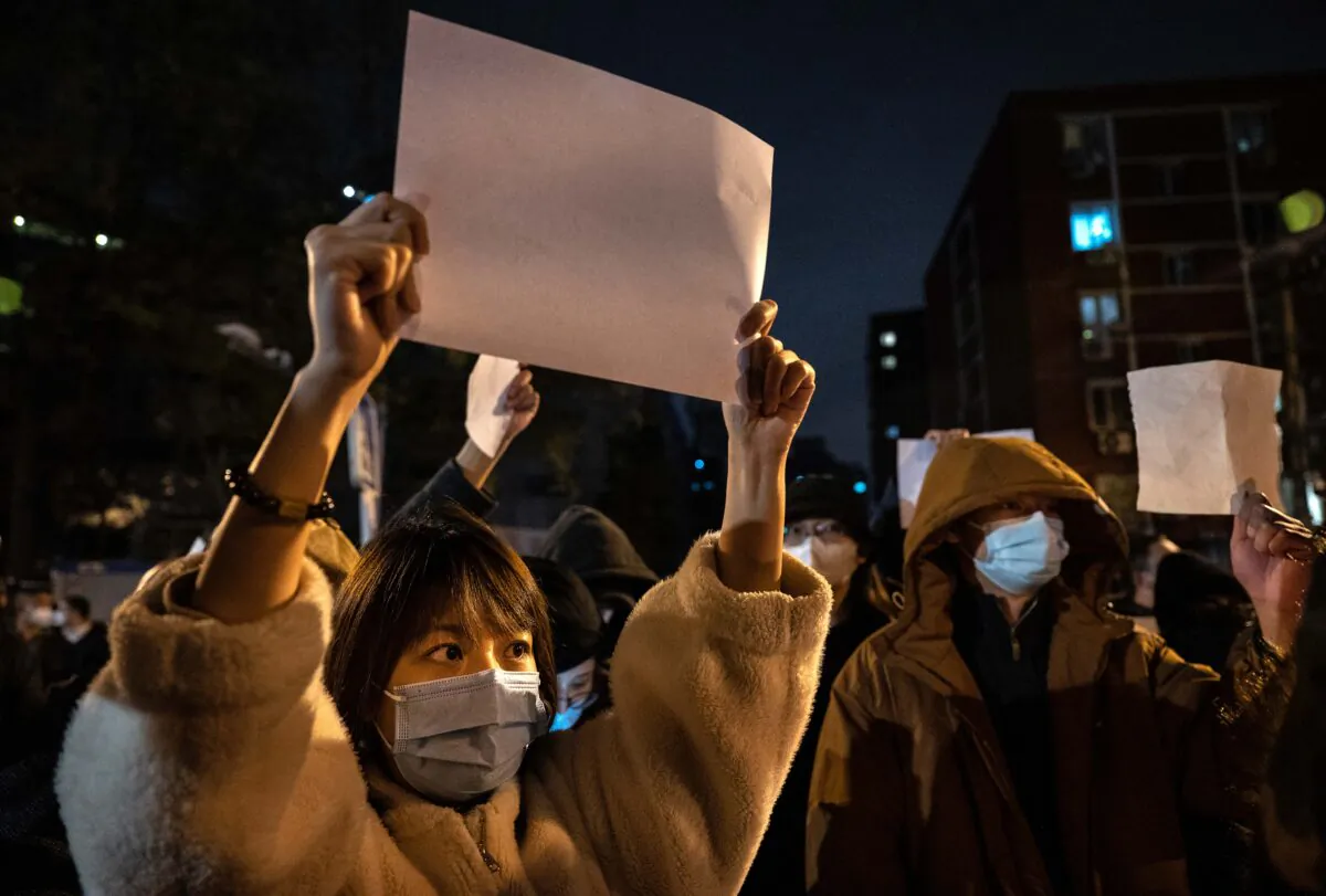 Protesters hold up pieces of paper protesting censorship and China's strict zero-COVID measures in Beijing on Nov. 27, 2022. (Kevin Frayer/Getty Images)