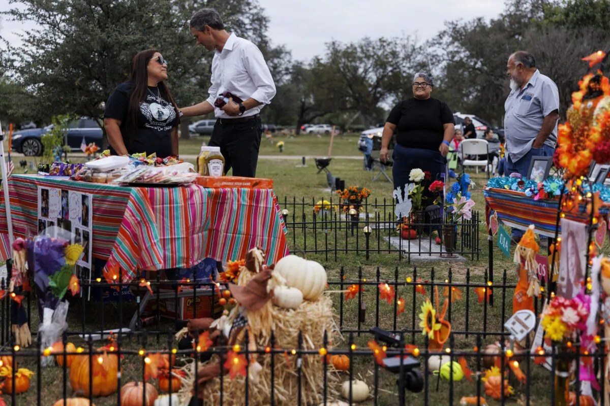 Sandra Cruz Torres, mother of Robb Elementary shooting victim Eliahna Torres, chats with Beto O'Rourke, Democratic candidate running for governor, as Cruz and her family celebrate Día de los Muertos at Torres' gravesite in Hillcrest Memorial Cemetery in Uvalde, Texas, on Nov. 2, 2022. (Sam Owens/The San Antonio Express-News via AP)