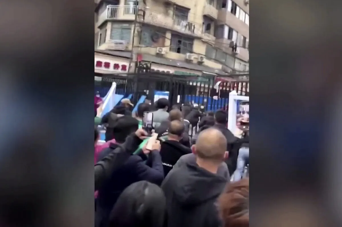 Protesters tear down structures surrounding compounds under lockdowns, in Wuhan, China, in a still from video released on Nov. 27, 2022. (Video obtained by Reuters/Screenshot via The Epoch Times)