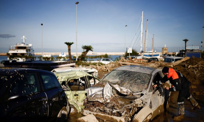 A member of the Coast Guard looks for documents inside a destroyed car, following a landslide on the Italian island of Ischia on Nov. 28, 2022. (Guglielmo Mangiapane/Reuters)