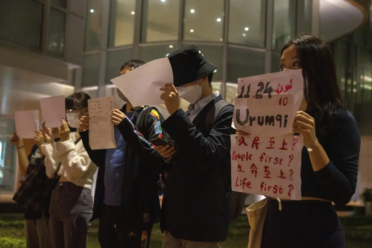 Protesters hold up white paper some with writings commemorating the Nov 24 deadly Urumqi fire during a gathering at the University of Hong Kong in Hong Kong on Nov. 29, 2022. (Bertha Wang/AP Photo)