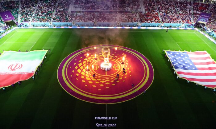 2022 年 11 月 29 日，在卡塔尔多哈的 Al Thumama 体育场举行的伊朗和美国比赛前，巨大的 FIFA 世界杯奖杯复制品和烟花与伊朗和美国国旗一起出现在球场上。（Fabrizio Bensch/路透社）