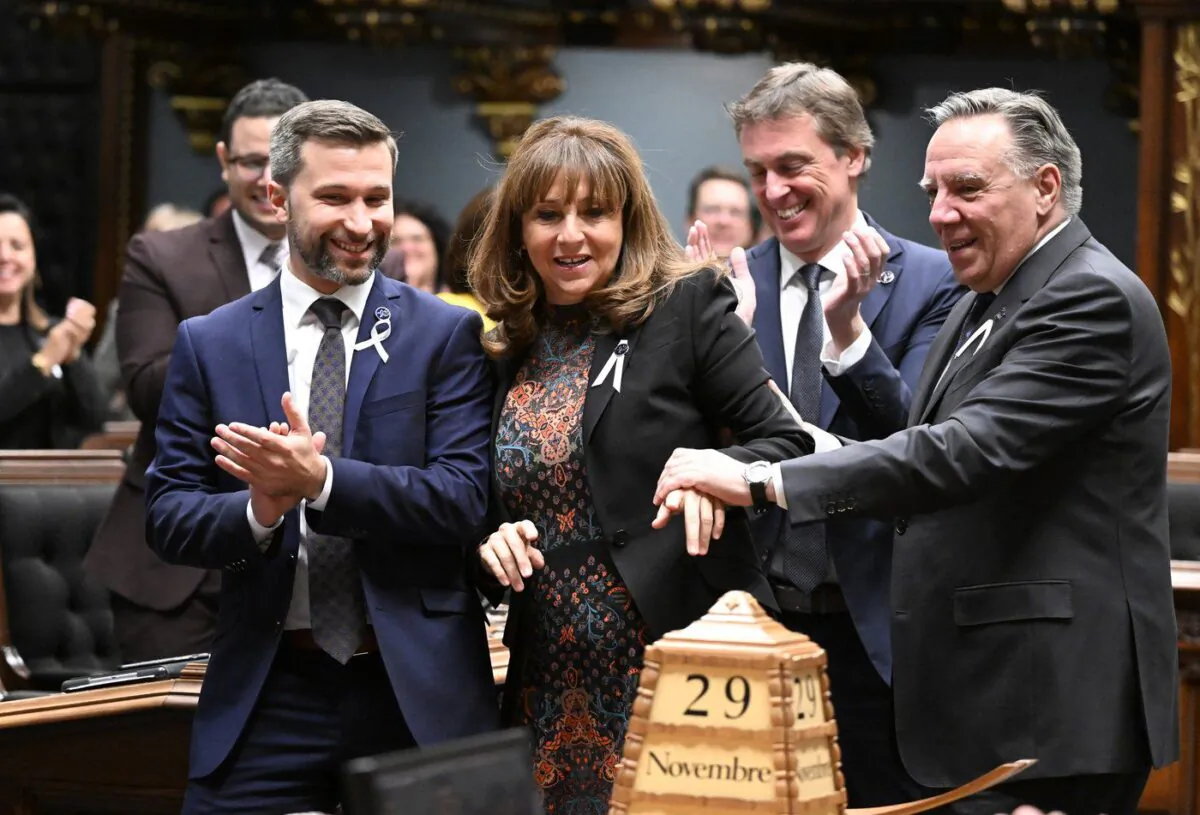 Elected House Speaker Nathalie Roy is carried to her seat by Quebec Premier Francois Legault, right, as Quebec Solidaire Leader Gabriel Nadeau-Dubois, left, and Quebec Liberal Party interim Leader Marc Tanguay applaud, Nov. 29, 2022 at the legislature in Quebec City. (The Canadian Press/Jacques Boissinot)
