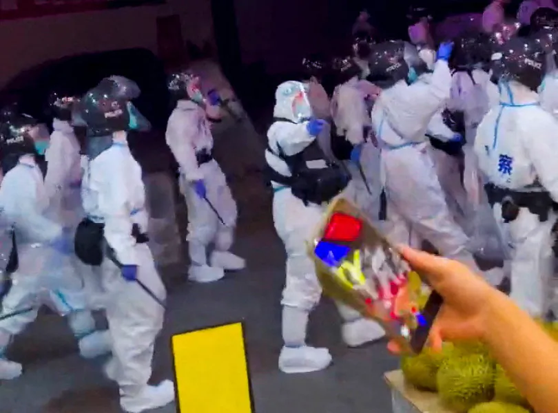 Riot police in personal protection suits walk down a street, during protests over COVID-19 restrictions in Guangzhou, a city in Guangdong Province, China, in this screen grab taken from a social media video released on Nov. 29, 2022. (Video Obtained by Reuters/via Reuters)