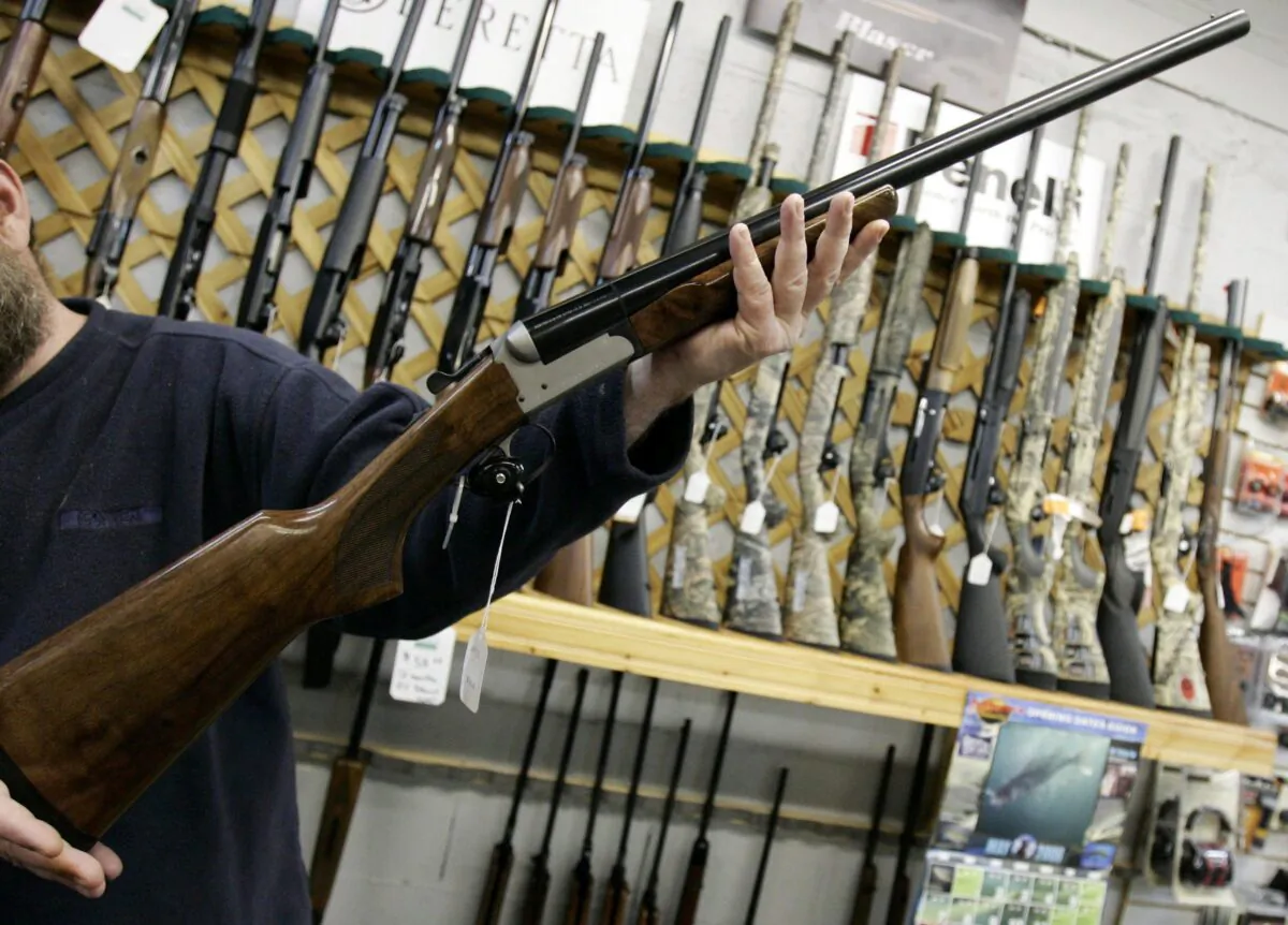 A salesman holds up a shotgun at a hunting store in Ottawa, in a file photo. (Jonathan Hayward/The Canadian Press)