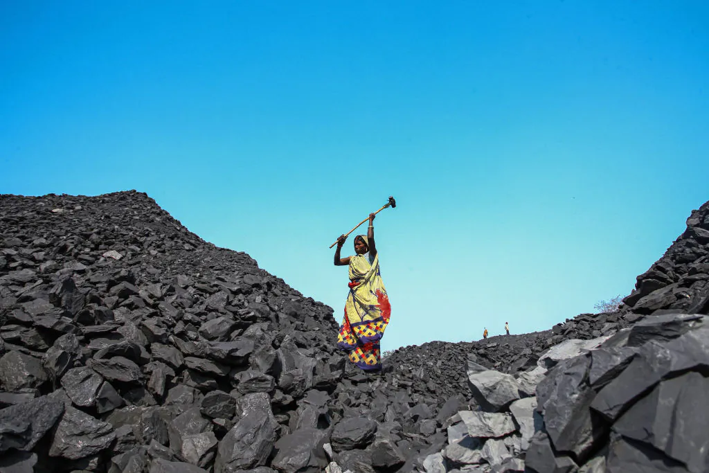 Workers break down coal at a coal yard near a mine in Sonbhadra, Uttar Pradesh, India, on Nov. 23, 2021. (Ritesh Shukla/Getty Images)