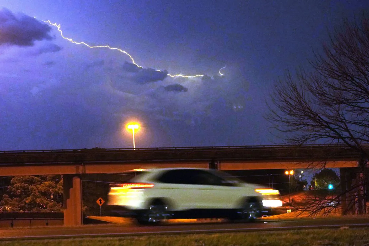 Lightning streaks across the sky as a vehicle races along a street in Jackson, Miss., on Nov. 29, 2022. (Rogelio V. Solis/AP Photo)