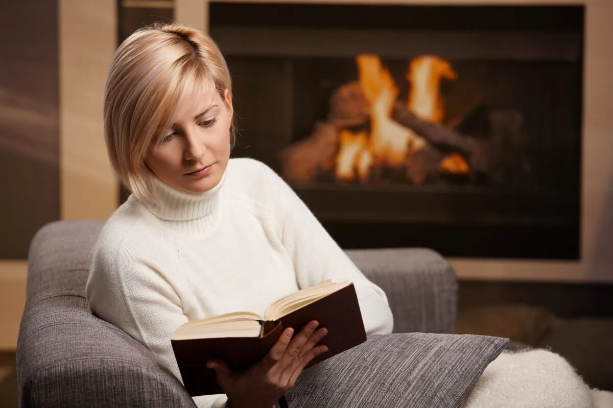 A healthy escape could be as simple as spending an hour with an enjoyable book by the fireplace. (StockLite/Shutterstock)