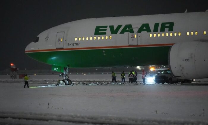 Workers are seen around an EVA Air Boeing 777 aircraft that went off a taxiway onto soft ground after landing at Vancouver International Airport from Taipei during a snowstorm on Nov. 30, 2022. (The Canadian Press/Darryl Dyck)
