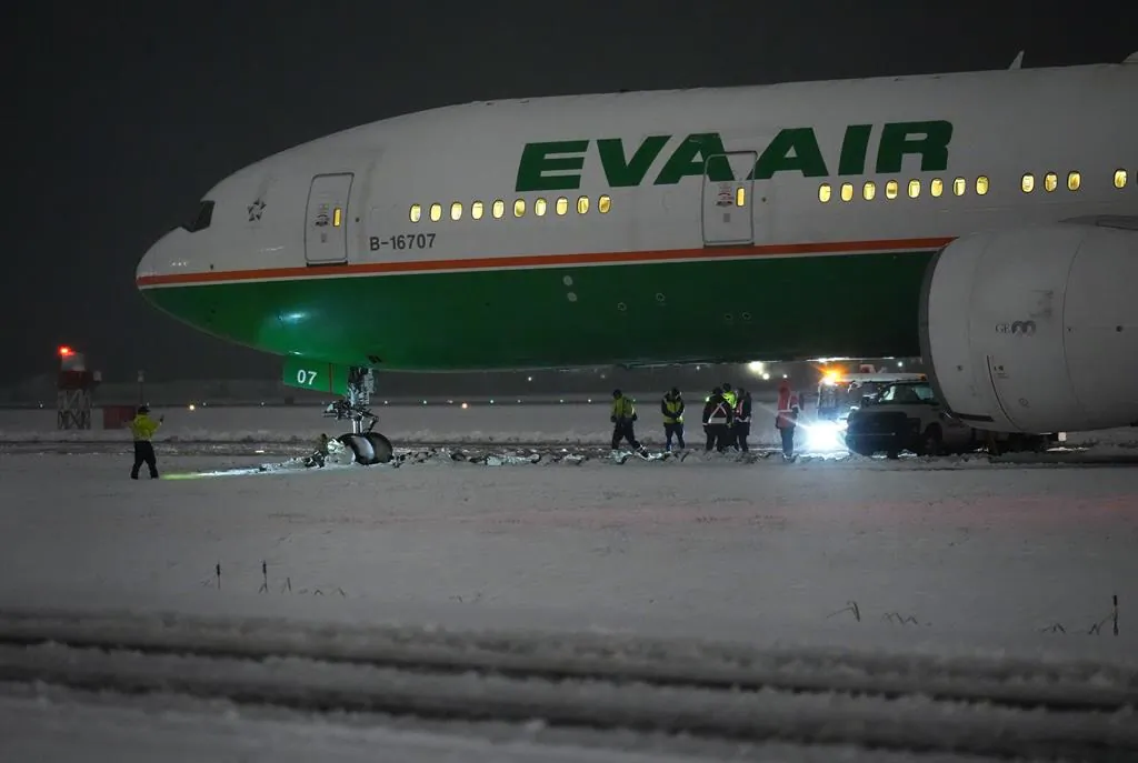 Workers are seen around an EVA Air Boeing 777 aircraft that went off a taxiway onto soft ground after landing at Vancouver International Airport from Taipei during a snowstorm on Nov. 30, 2022. (The Canadian Press/Darryl Dyck)

