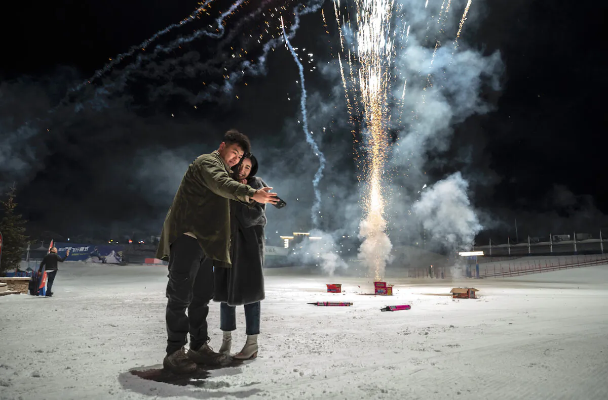 A couple takes a selfie as revelers fire off firecrackers to celebrate the new year at a ski resort in Chongli, Hebei Province, China, on Jan. 1, 2023. (Kevin Frayer/Getty Images)