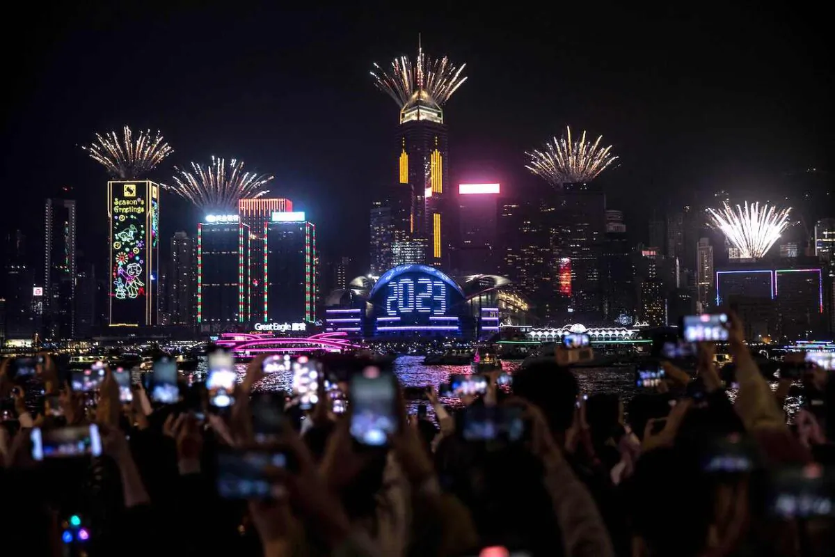 Revellers watch a fireworks and laser show as they celebrate the New Year next to Victoria Harbour in Hong Kong on Jan. 1, 2023. (Isaac Lawrence/AFP via Getty Images)