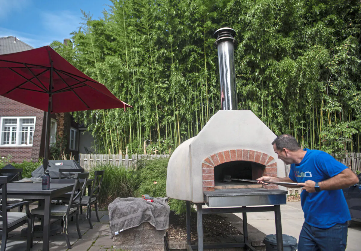 Chris Hayes moves around embers in his pizza oven in his Ben Avon backyard, in Pennsylvania, on Saturday, Sept. 24, 2022. (Emily Matthews/Pittsburgh Post-Gazette/TNS)