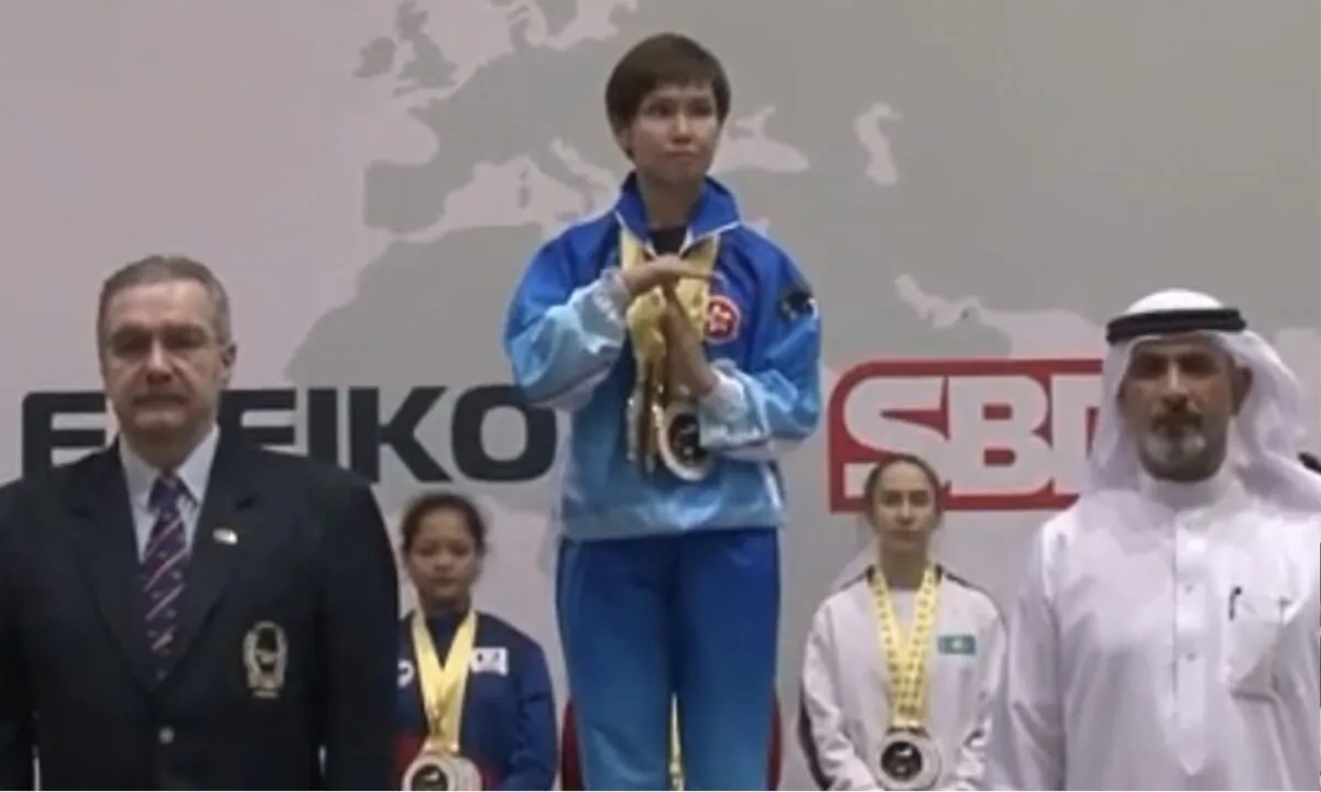 Hong Kong representative Suanna Lin made a “T” gesture to indicate the song played by the organizer was wrong when the English version of pro-democracy song Glory to Hong Kong was played instead of the CCP anthem. (Screenshot of Youtube Video)