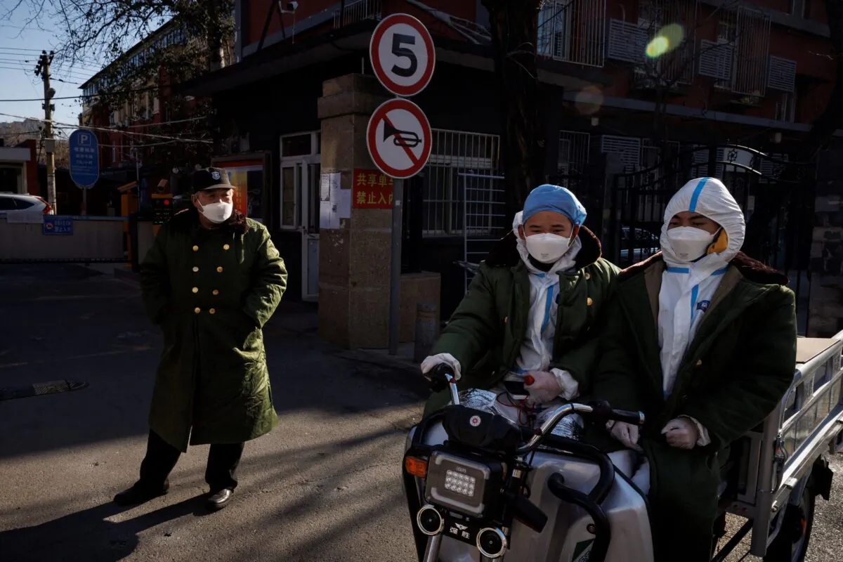 Pandemic prevention workers in protective suits ride an electric vehicle in Beijing on Dec. 4, 2022. (Thomas Peter/Reuters)