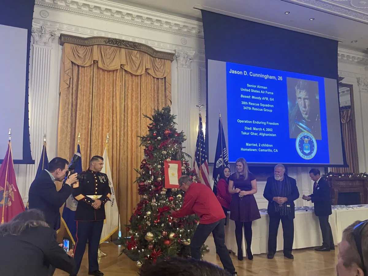 Loved ones of late veteran Jason Cunningham hang commemorative ornaments on tree during The Nixon Library's Hometown Heroes Ceremony in Yorba Linda, Calif., on Dec. 4, 2022. (Carol Cassis/The Epoch Times)