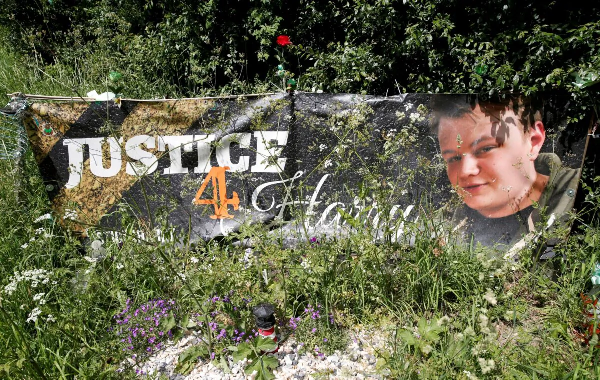 A banner and a memorial area for British teenager Harry Dunn who died in a road traffic collision is pictured near to the entrance of RAF Croughton, in Croughton, near Brackley, Britain, on June 11, 2021. (Andrew Boyers/Reuters)