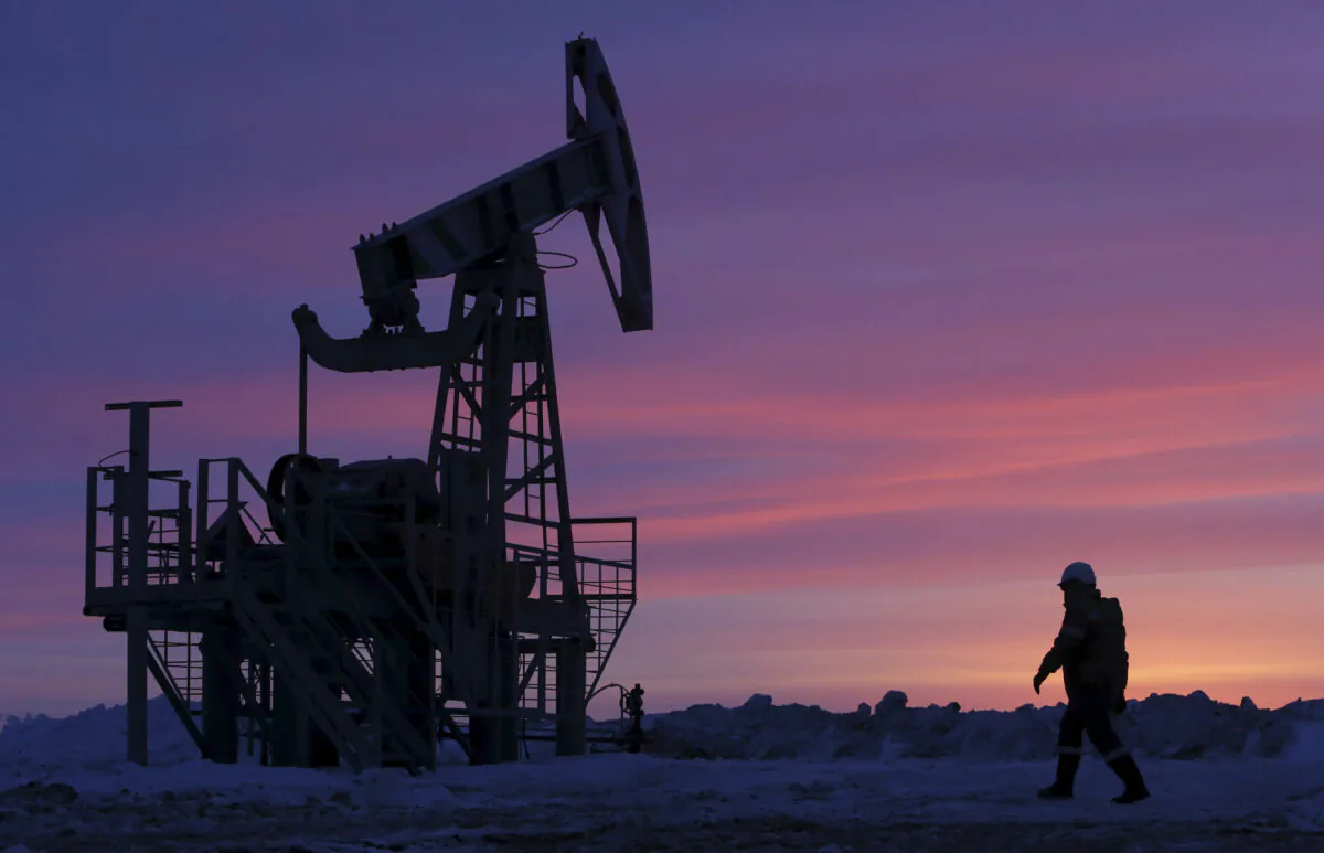 A worker walks past a pump jack on an oil field owned by Bashneft company near the village of Nikolo-Berezovka, northwest from Ufa, Bashkortostan, Russia, on Jan. 28, 2015. (Sergei Karpukhin/Reuters)