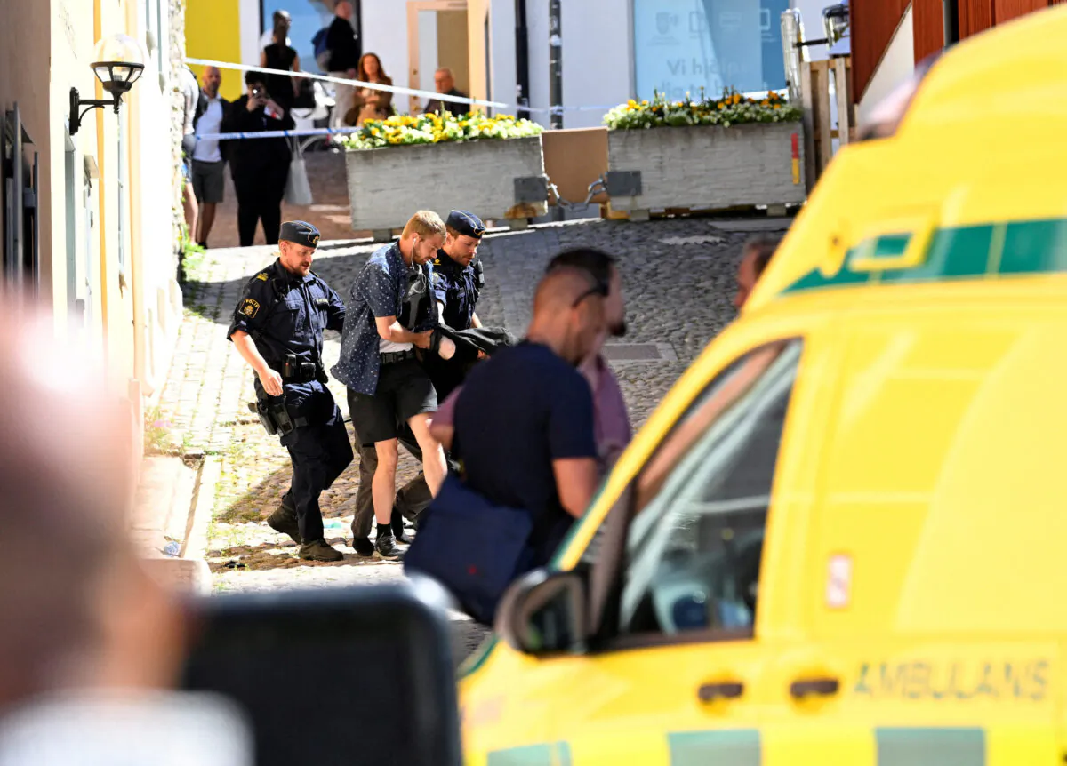Police officers escort the apprehended male suspect after a woman was seriously injured in a stabbing at the Almedalen political festival at Visby on Gotland island, Sweden, on July 6, 2022. (TT News Agency/Henrik Montgomery via Reuters)