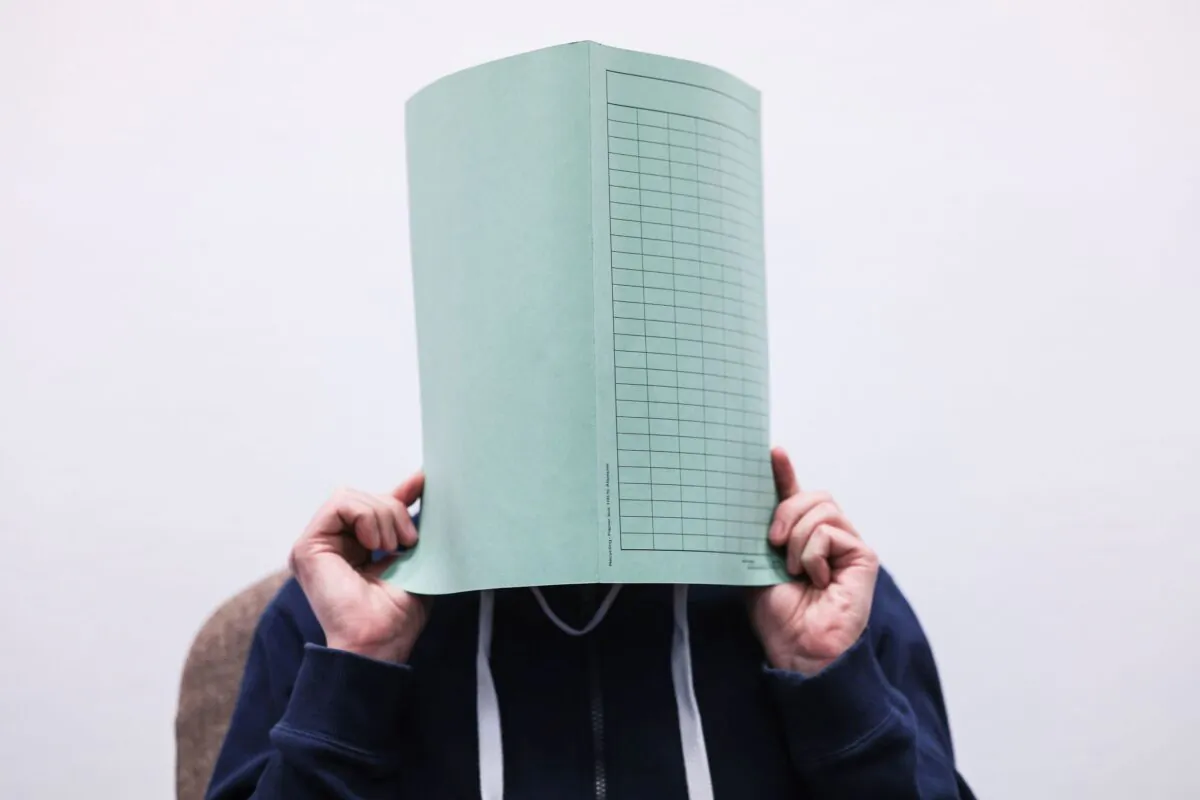 The defendant in the Wermelskirchen abuse complex holds a folder in front of his face in the courtroom in Cologne, Germany, on Dec. 6, 2022. (Oliver Berg/dpa via AP)