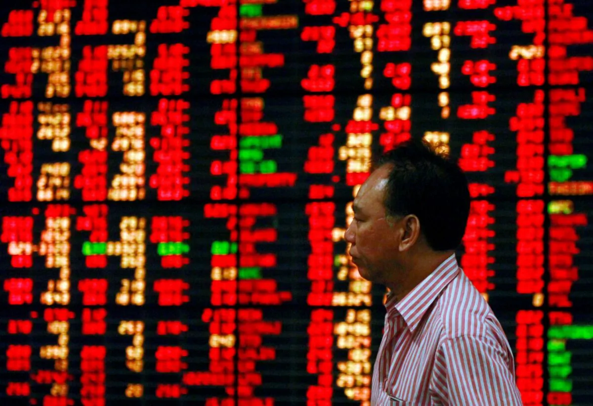 A Thai investor walks past an electronic board displaying live market data at a stock broker's office in central Bangkok on Aug. 9, 2011. (Chaiwat Subprasom/Reuters)