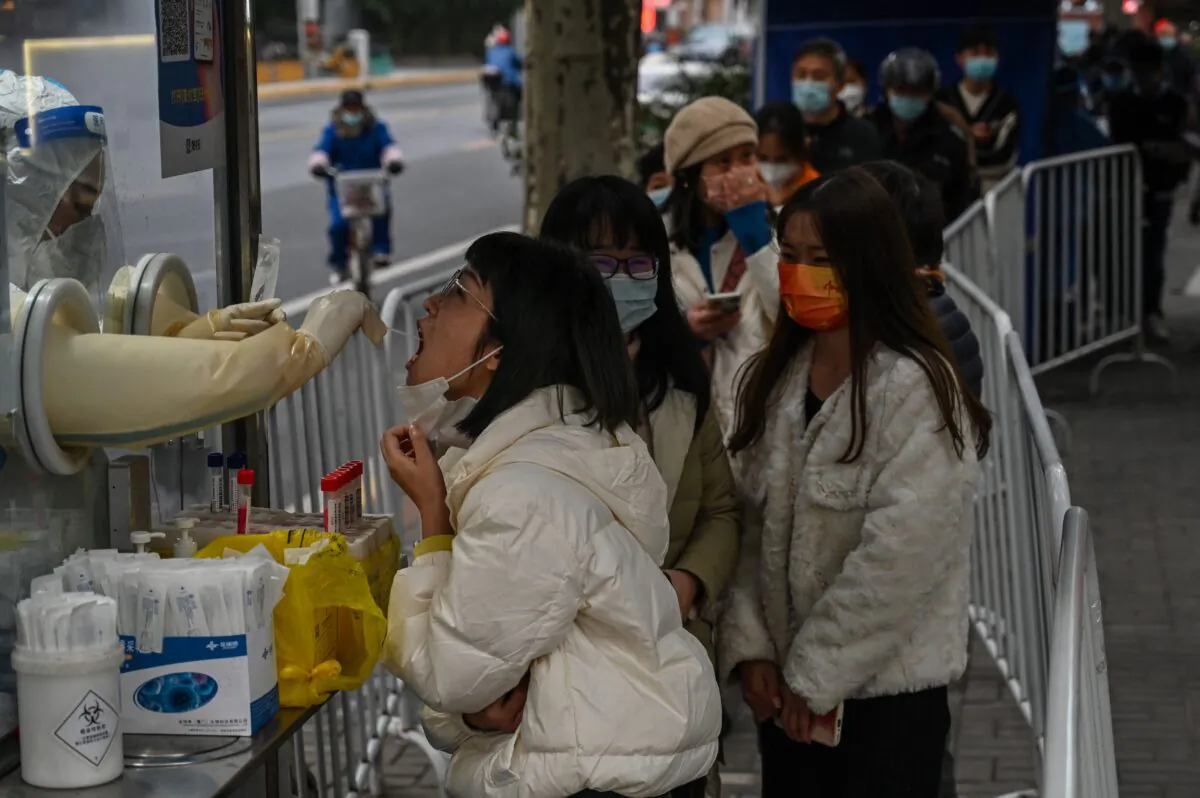A health worker takes a swab sample from a woman to test for the Covid-19 coronavirus in the Jing'an district in Shanghai on December 7, 2022. (Hector Retamal / AFP via Getty Images)