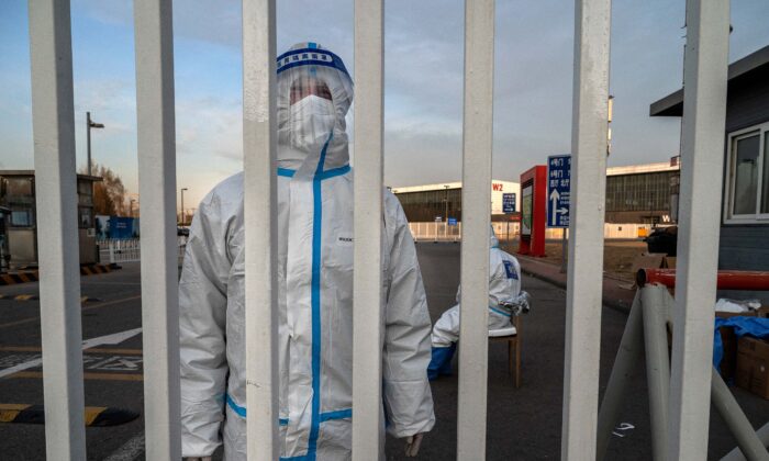 2022 年 12 月 7 日，一名防疫工作人员守卫着北京政府检疫设施的大门。（Kevin Frayer/Getty Images）