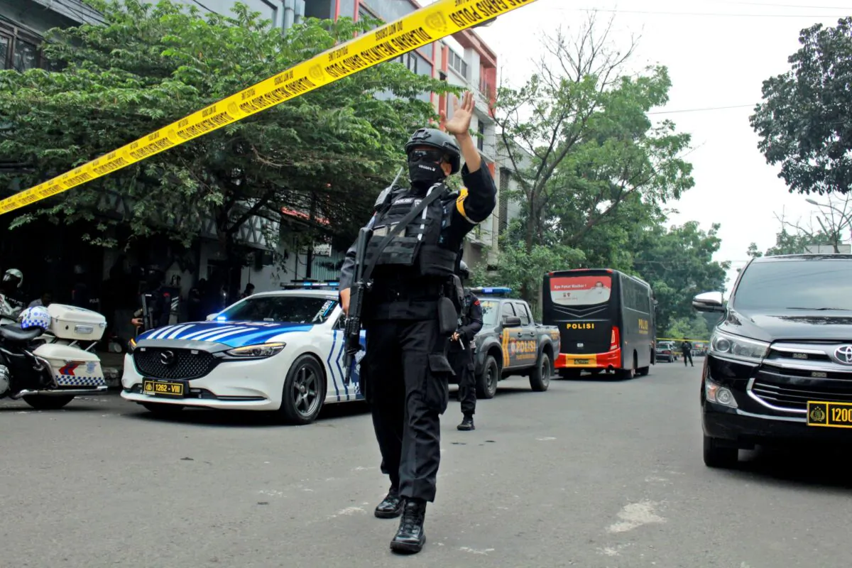 A police officer gestures at the crowd to move back as he guards a road leading to a police station where a bomb exploded in Bandung, West Java, Indonesia, on Dec. 7, 2022. (Kholid Parmawinata/AP Photo)
