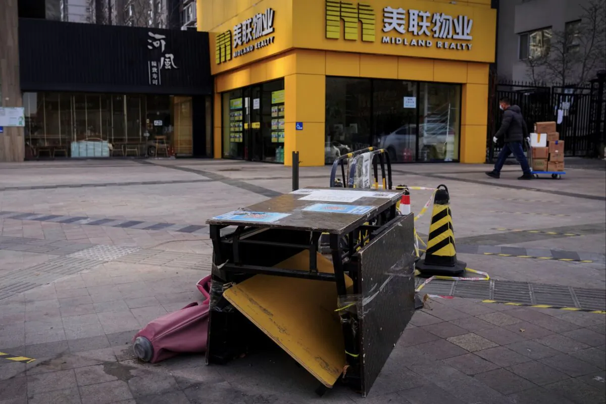A worker moves goods past a dismantled COVID-19 testing site outside shops after authorities start easing some of the anti-virus controls in Beijing on Dec. 7, 2022. (Andy Wong/AP Photo)