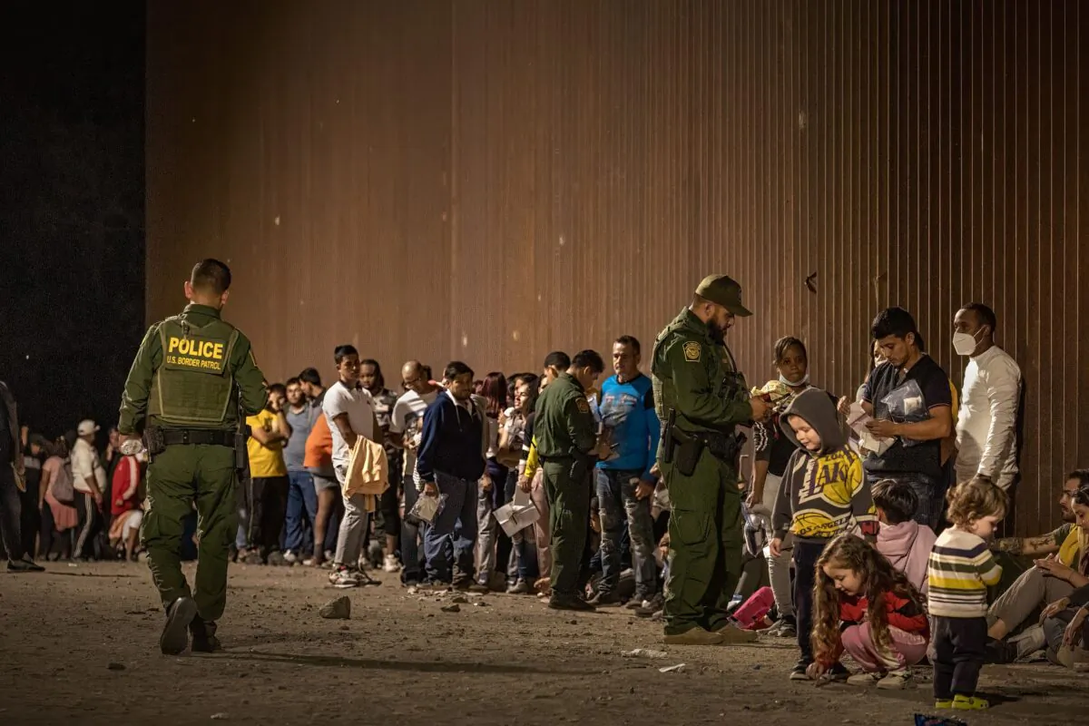 U.S. Border Patrol agents check for identification of immigrants as they wait to be processed after crossing the border from Mexico in Yuma, Ariz., on June 22, 2022. (Qian Weizhong/VCG/Getty Images)