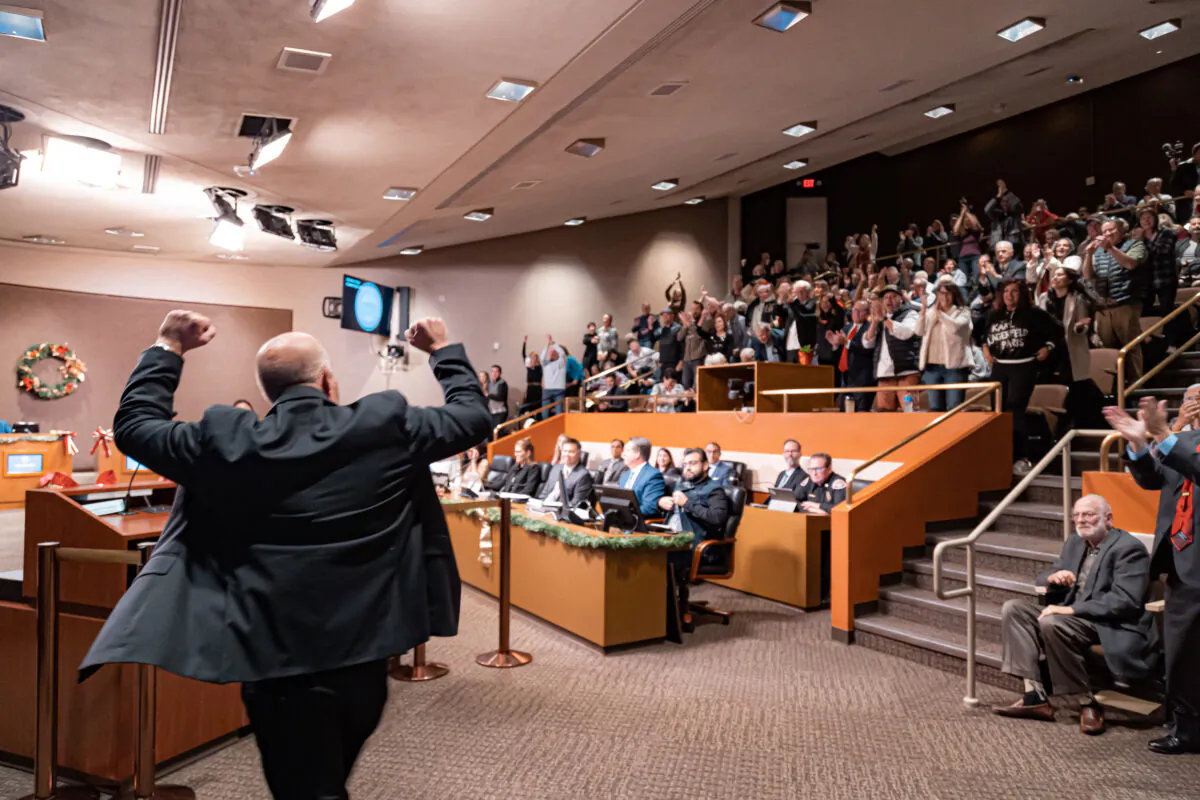 Newly-elected Huntington Beach City Councilman Pat Burns pumps his fists in response to the crowd’s standing ovation as he walks up to be sworn into office in Huntington Beach, Calif., on Dec. 6, 2022. (Julianne Foster/The Epoch Times)