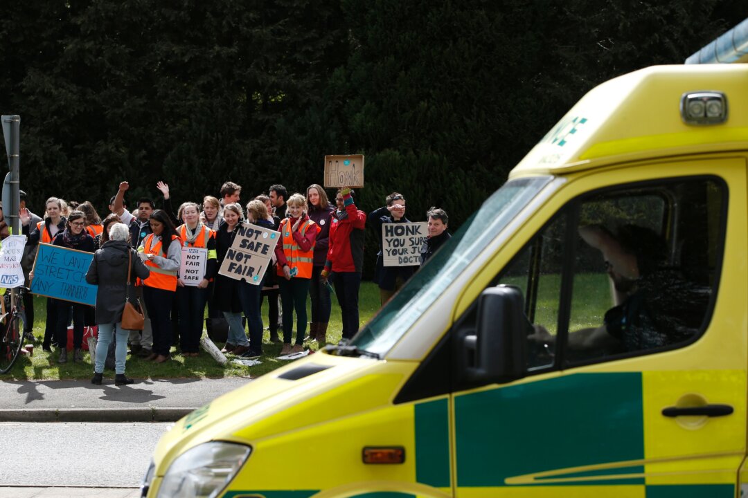 In this file image, an ambulance passes demonstrators protesting  during a strike by junior doctors outside the Basingstoke and North Hampshire Hospital on April 26, 2016. (Adrian Dennis/AFP via Getty Images)