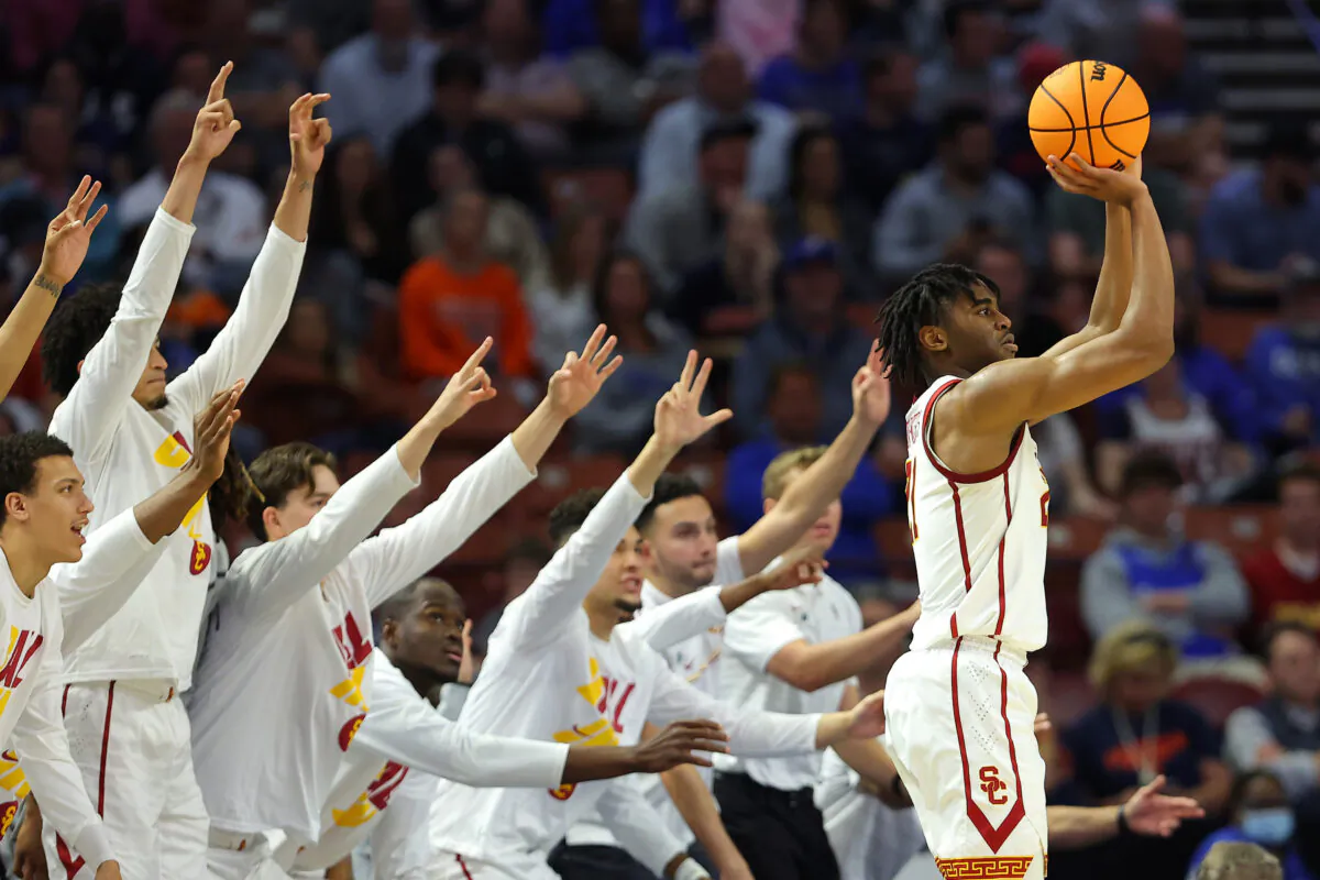 Reese Dixon-Waters (21) of the USC Trojans shoots and scores a three pointer as the USC Trojans bench reacts during the second half in the first round game of the 2022 NCAA Men's Basketball Tournament at Bon Secours Wellness Arena in Greenville, S. C., on March 18, 2022. (Kevin C. Cox/Getty Images)